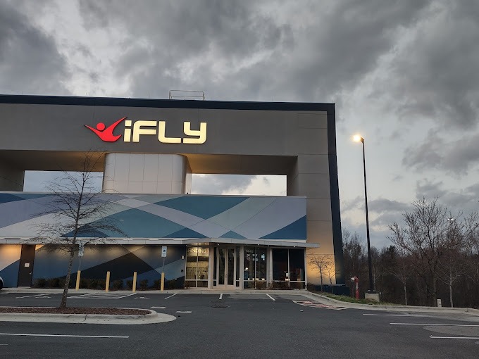 A gray modern building with an "iFly" sign, known for offering indoor skydiving experiences, ideal for thrill-seekers. This location is one of the best birthday party venues in Charlotte NC, perfect for those looking for exciting and unique birthday venues in Charlotte NC.