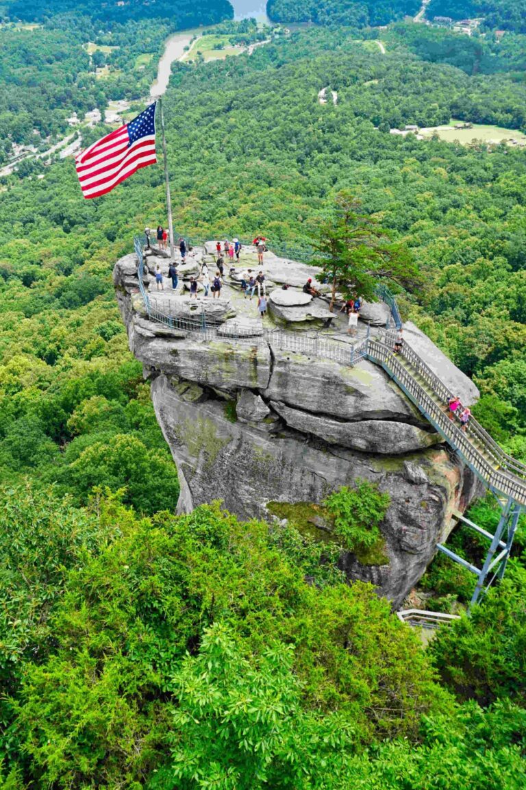 A group of people standing on a cliff with Chimney Rock State Park in the background, one of the scenic birthday party venues in Charlotte NC. This picturesque location is a fantastic choice for celebrating a birthday in Charlotte, offering breathtaking views and outdoor adventure.